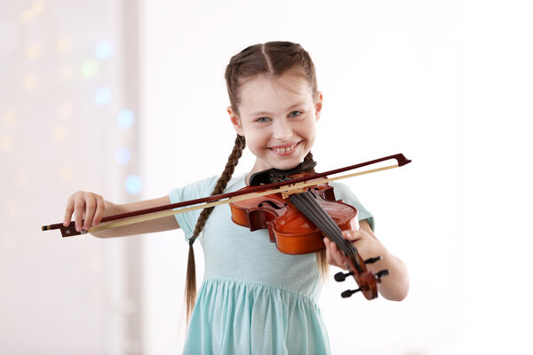 Маленькая девочка играет на скрипке
