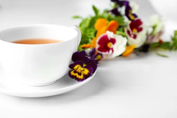 Mooi boeket van viooltjes en cup — Stockfoto