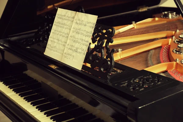 Музыкальные ноты на чёрном пианино — стоковое фото