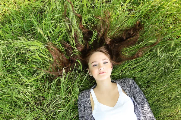 Menina que estabelece na grama verde — Fotografia de Stock