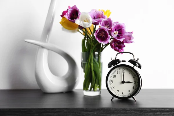 Alarm clock with tulips bouquet — Stock Photo, Image