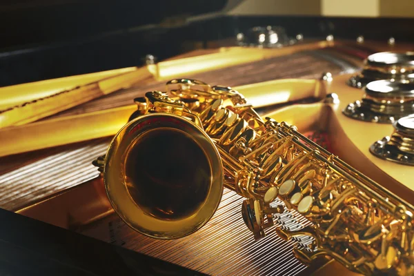 Saksofon, leżącego na fortepian — Zdjęcie stockowe