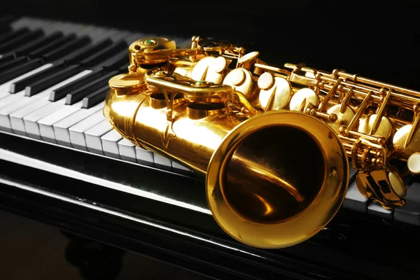 Saxofon liggande på piano — Stockfoto