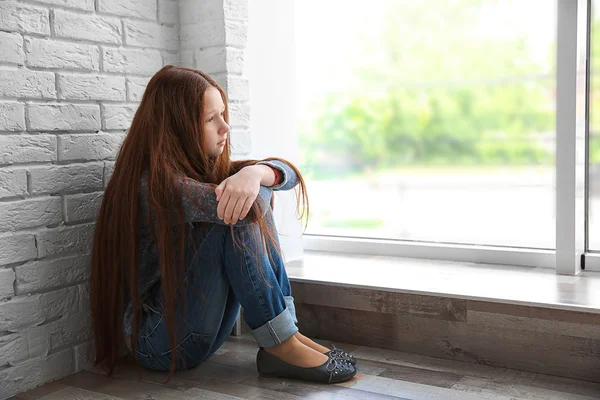 Smutná dívka sedí u okna — Stock fotografie
