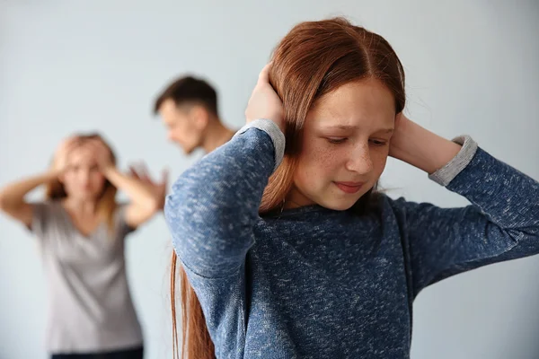 Family problems concept. Girl closing her ears while parents abusing