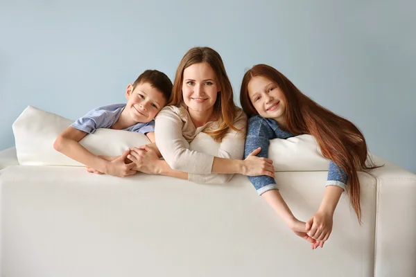 Smiling mother with children on sofa — Stock Photo, Image