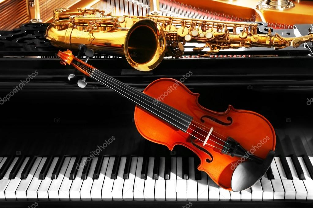 Violin and saxophone lying on piano Stock Photo by