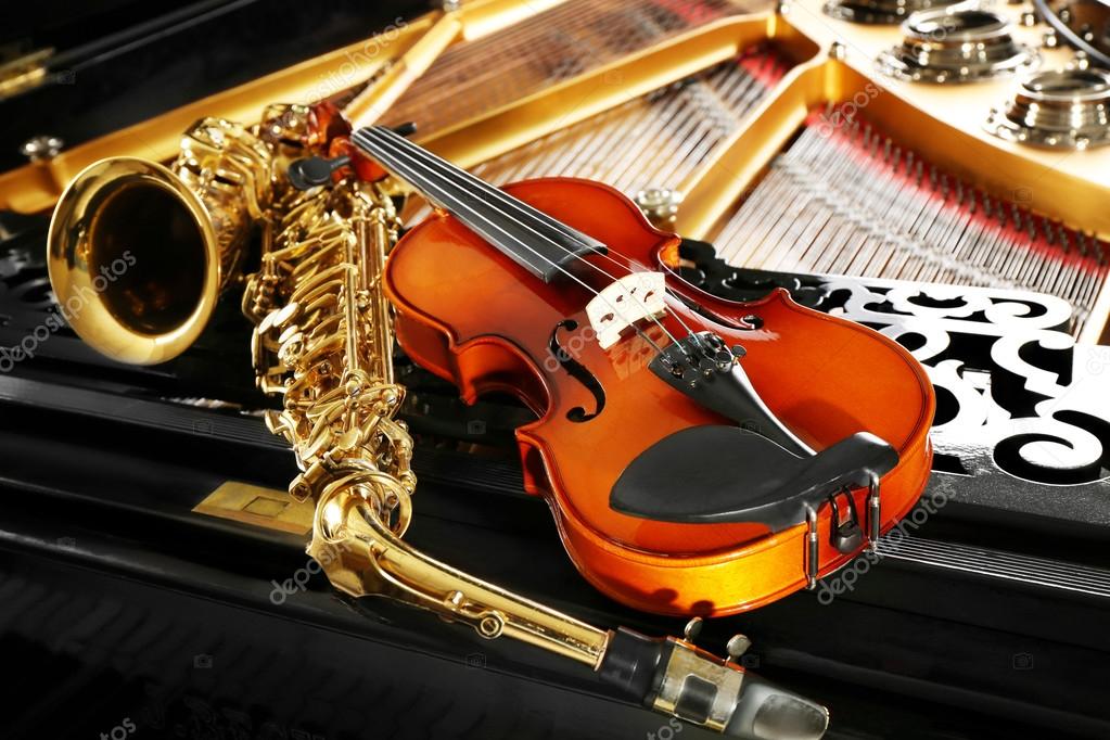 Violin and saxophone lying on piano — Stock Photo © belchonock 115910654