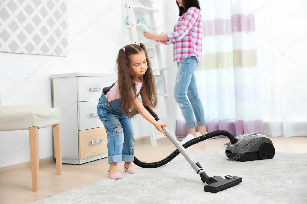 Daughter and mother using vacuum cleaner in room