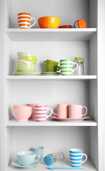 Tableware on shelves in cupboard — Stock Photo, Image