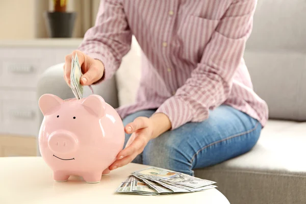 Hand geld steken in piggy bank — Stockfoto