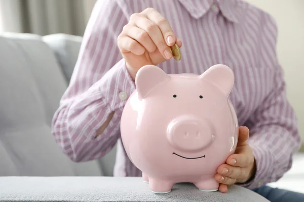 Mão colocando dinheiro no banco porquinho — Fotografia de Stock