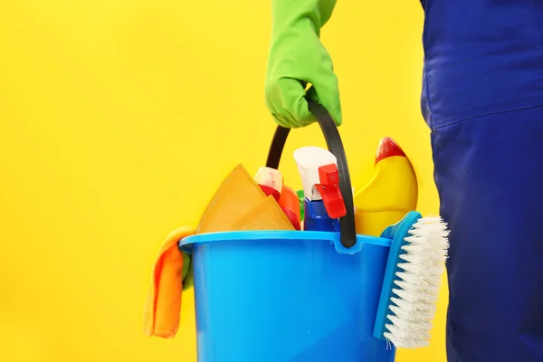 Mão segurando balde de plástico com escovas — Fotografia de Stock