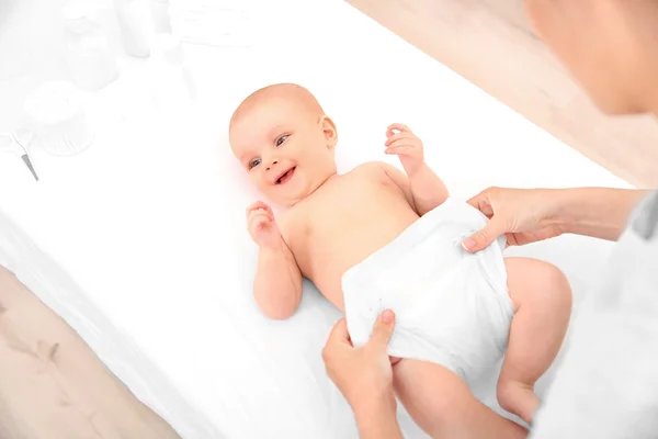 Mãe mudando fralda para bebê na mesa — Fotografia de Stock