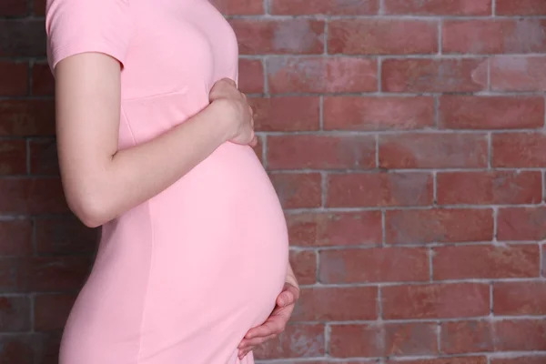 Gravid kvinna på tegelvägg — Stockfoto