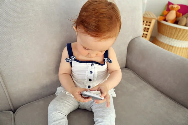 Lindo bebê brincando com telefone no sofá — Fotografia de Stock