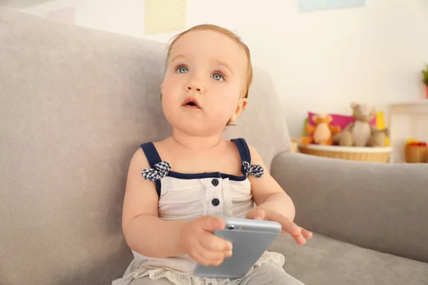 Lindo bebê brincando com telefone no sofá — Fotografia de Stock