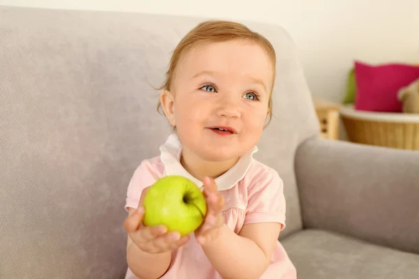 Beautiful Baby with apple on sofa in room — Stock Photo, Image