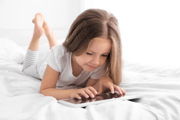 Nettes kleines Mädchen spielt mit Tablet — Stockfoto