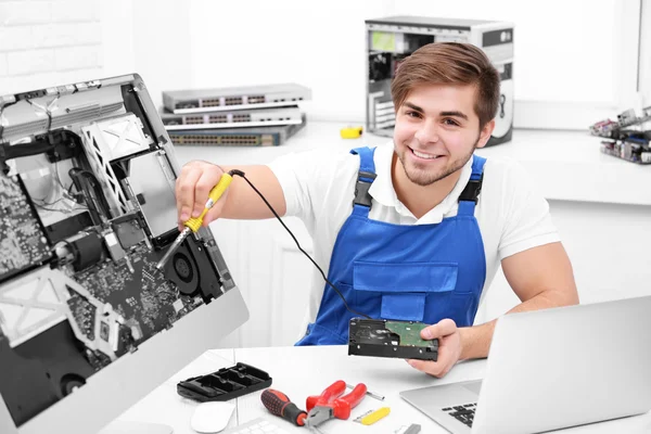 Joven reparador trabajando con soldador en el centro de servicio — Foto de Stock