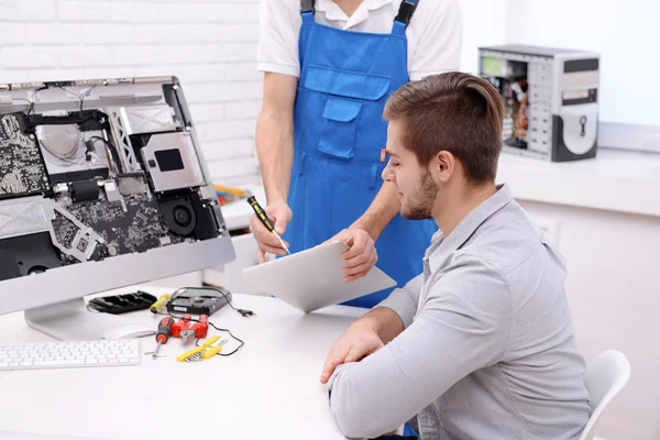 Master showing the repair process to young man in service center — Stock Photo, Image