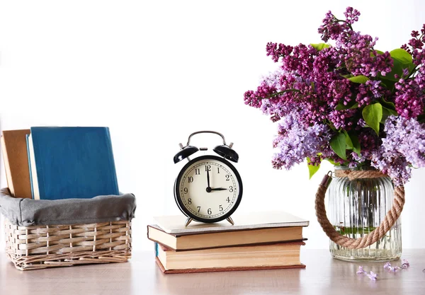 Alarm clock with lilac bouquet — Stock Photo, Image