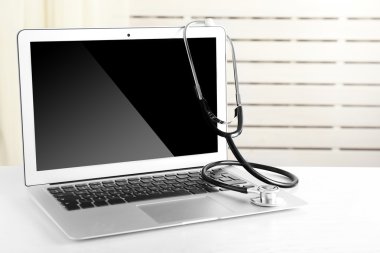 Modern dizüstü ve ışık arka plan üzerinde stetoskop
