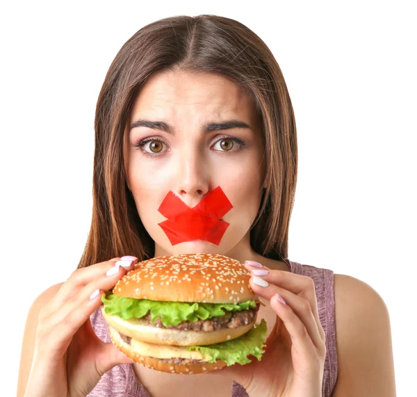 Woman with tied mouth holding hamburger — Stock Photo, Image