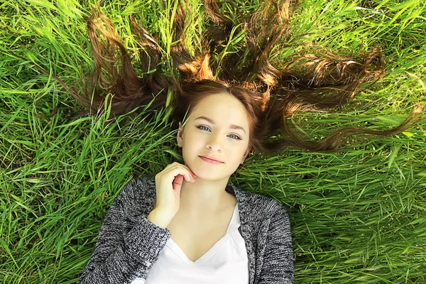 Menina que estabelece na grama verde — Fotografia de Stock