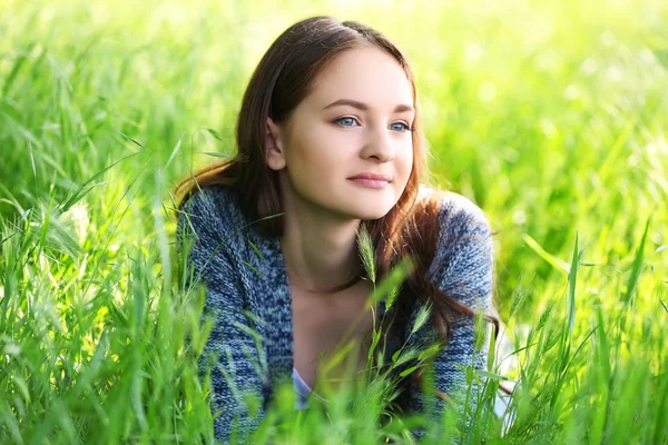 Menina que estabelece na grama verde — Fotografia de Stock