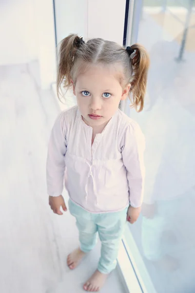 Маленькая симпатичная девочка на подоконнике — стоковое фото