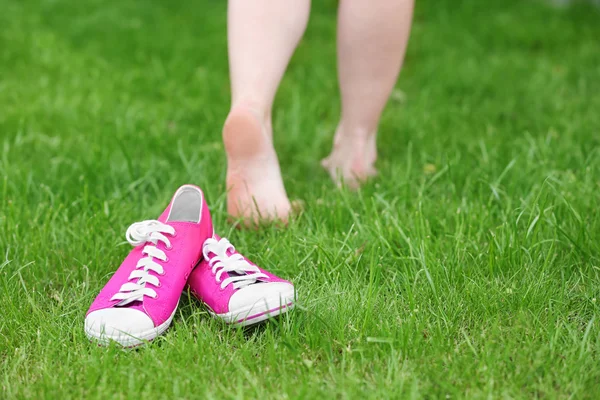 Vrouwelijke sneakers opleggen van groen gras — Stockfoto