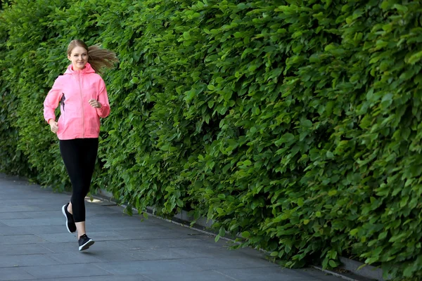 Femme sportive jogging au parc par une journée ensoleillée — Photo