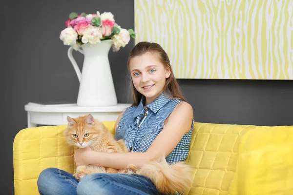 Hermosa chica con lindo gato en el sofá amarillo —  Fotos de Stock