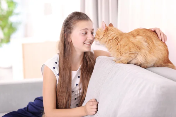 Schönes Mädchen mit süßer Katze auf grauem Sofa — Stockfoto