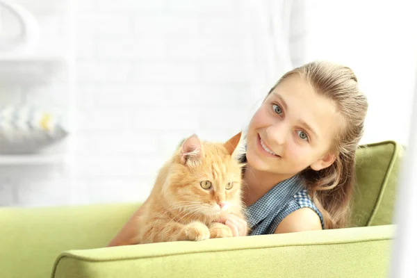 Mooi meisje met schattige kat op groene fauteuil — Stockfoto