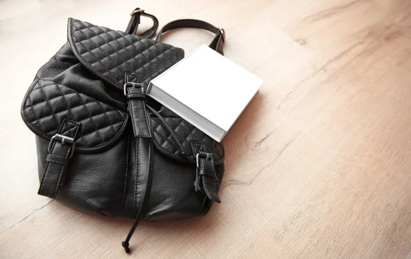 Кожаный рюкзак и книга — стоковое фото