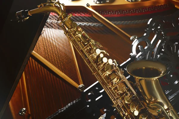 Saxofon, ležící na klavír — Stock fotografie