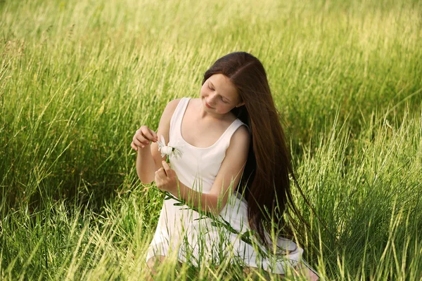 Söt flicka i äng med kamomillblommor — Stockfoto