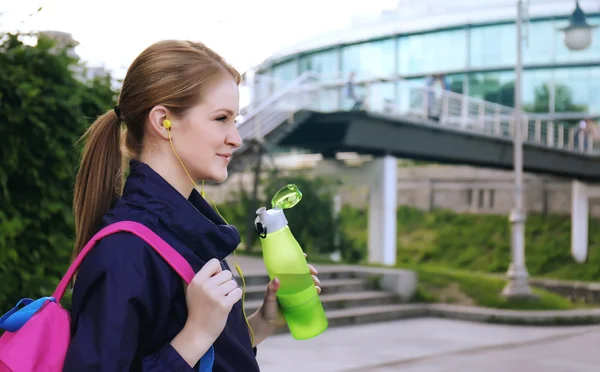 Mulher desportiva beber água depois de correr no parque em um dia ensolarado — Fotografia de Stock
