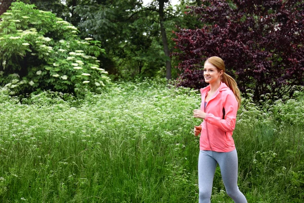 Deportiva mujer corriendo en el parque en un día soleado — Foto de Stock