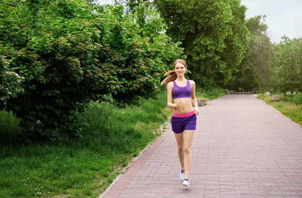 Sporty woman jogging at park on a sunny day — Stock Photo, Image