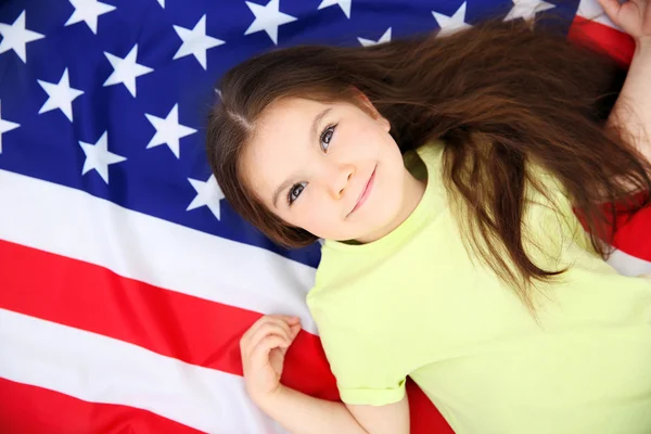 Menina bonito deitado na bandeira nacional americana — Fotografia de Stock