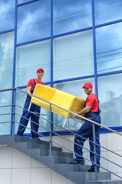 Dois trabalhadores do sexo masculino com sofá amarelo em escadas — Fotografia de Stock