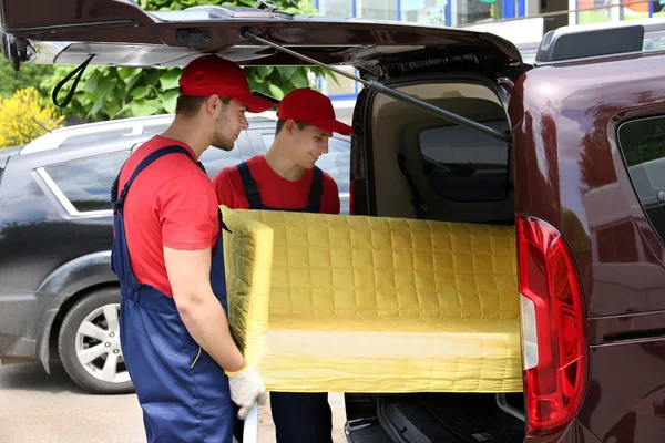 Twee mannelijke werknemers lossen gele Bank uit auto — Stockfoto