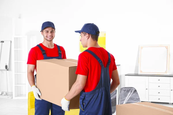 Trabajadores masculinos con cajas y muebles en casa nueva — Foto de Stock