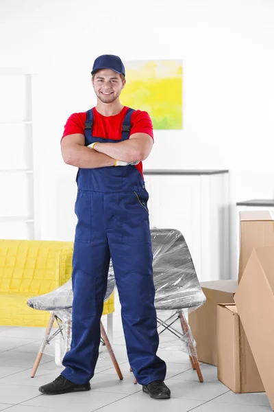 Travailleur masculin avec des boîtes et des meubles dans une maison neuve — Photo