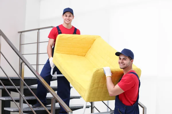 Zwei männliche Arbeiter mit gelbem Sofa im Treppenhaus — Stockfoto