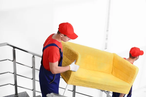 Twee mannelijke werknemers met gele luie stoel op trappen — Stockfoto