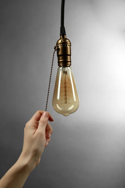 Hand turning on light bulb — Stock Photo, Image